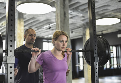 Man assisting woman exercising in gym