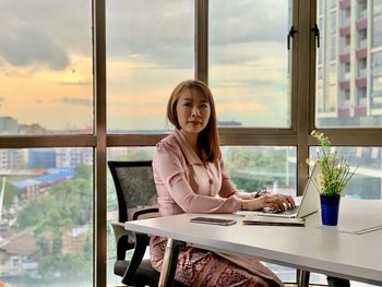 Portrait of woman sitting on table at window