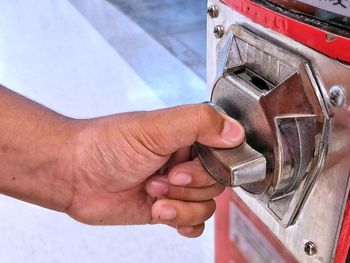 Close-up of hand turning knob of machine