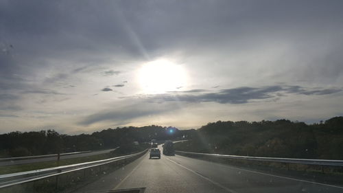 Country road against cloudy sky on sunny day