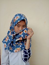 Full length portrait of girl standing against wall