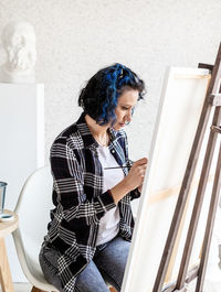 Woman looking away while standing against wall