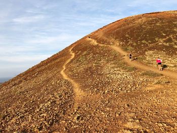 People on arid landscape against sky