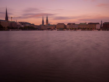 View of buildings by river against cloudy sky