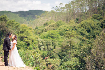 Side view of young couple on landscape against mountain