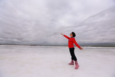 Full length of woman standing on snow covered landscape against sky