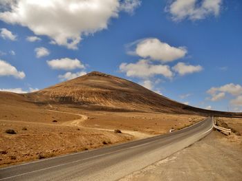 Empty road in desert against sky