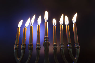 Lit menorah in celebration of hanukah against colored background