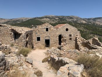 Old building by mountains against clear sky