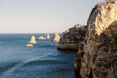 Rock formation in sea against clear sky