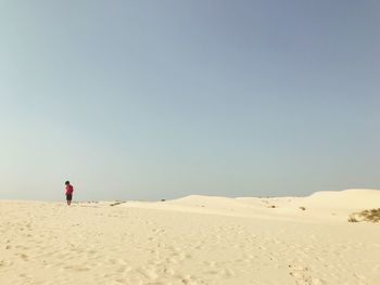 Boy standing at beach against clear sky