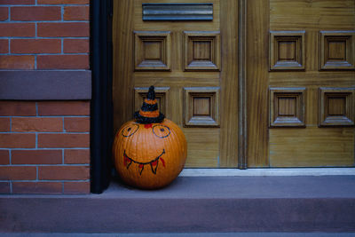 Halloween decoration of a pumpkin in a hat at the stoop of a building