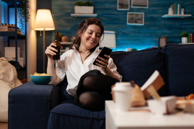 Young woman using mobile phone while sitting on sofa at home