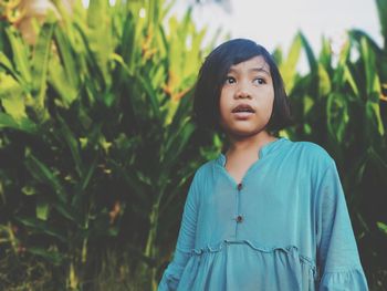 Portrait of teenage girl standing against plants