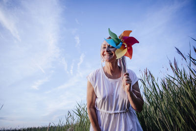 Girl with multicolored pigtails , face sideways, laughing, holding a windmill , wind energy