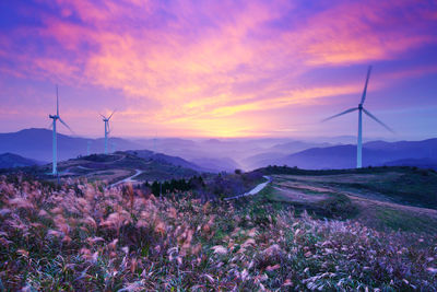 Windmills on mountains against sky during sunset