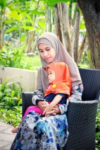 Full length of happy woman sitting outdoors