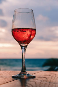 Close-up of wineglass on table next to the beach 