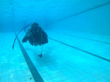 Portrait of scuba diver showing ok sign while swimming in pool