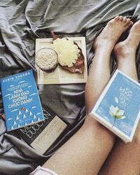 High angle view of man reading book on bed