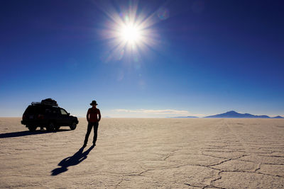 Silhouette man on barren landscape against blue sky