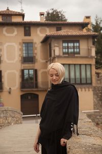 Portrait of woman standing against building