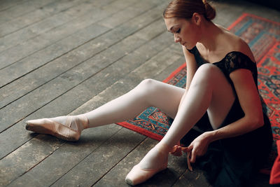 Woman wearing ballet shoe on floorboard