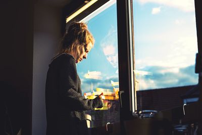 Side view of woman looking through window