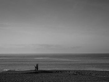 Couple walking at beach against sky