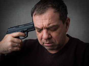 Close-up of man with gun against wall