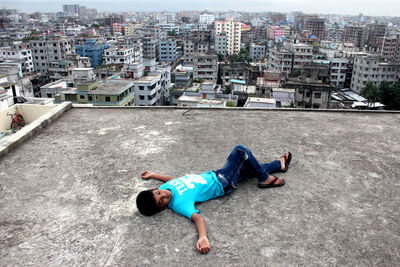 High angle view of boy lying on building terrace