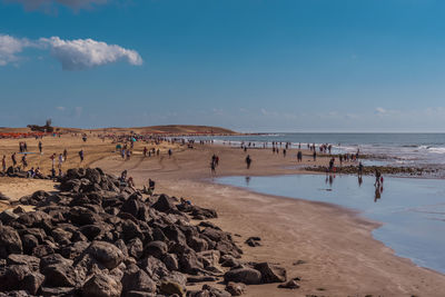 People at beach against blue sky