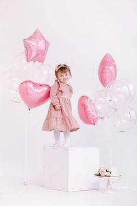 High angle view of girl with pink balloons against white background