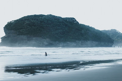 Person swimming in sea against clear sky