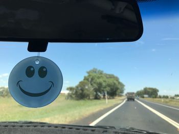 Close-up of car windshield on road against sky