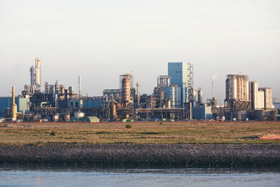Industrial buildings next to a waterway shipping canal in rotterdam port.