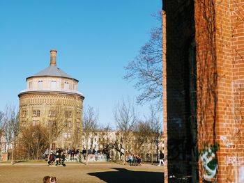 People in front of building against clear blue sky