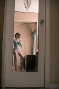 Reflection of young woman wearing bodysuit on mirror at home
