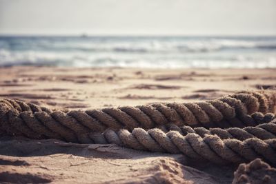 Close-up of rope on sand at beach against sky