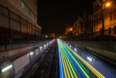 Light trails on road amidst buildings at night