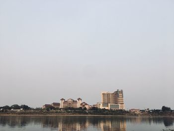 Lake by buildings against clear sky