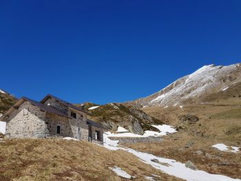 Low angle view of snowcapped mountain against clear blue sky