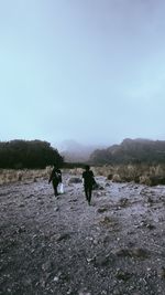 Rear view of people walking on land against sky