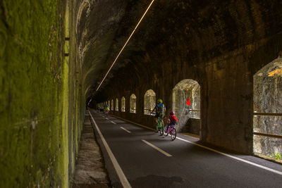 Rear view of girl with father riding bicycle in tunnel