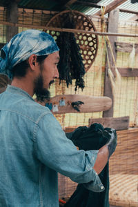 Man holding clothing while standing in shed