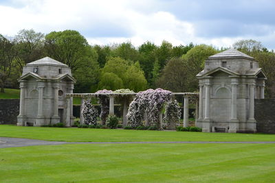 Built structure by trees on field against sky in lawn