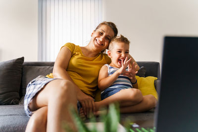 Full length of happy woman using mobile phone at home