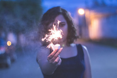 Close-up of woman hand holding sparkler at night