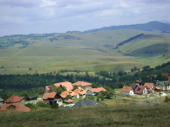 Houses on field by mountains against sky