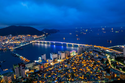 High angle view of illuminated cityscape by sea against sky